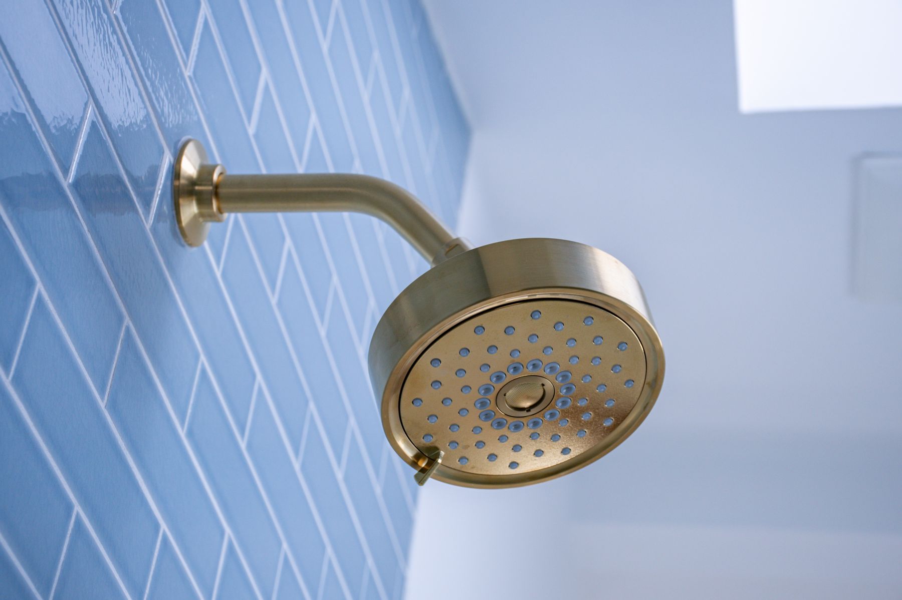 Bathroom with brass shower fixture finished by Revive Design Build